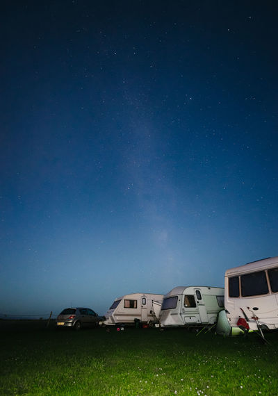 Scenic view of motor home on field against sky at night