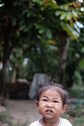 Portrait of cute girl standing against trees