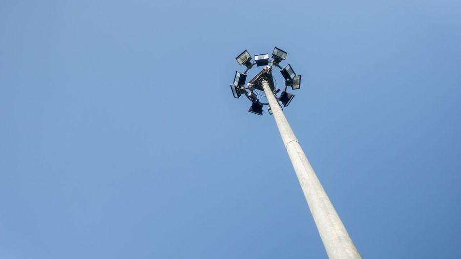 Low angle view of telephone pole against clear blue sky