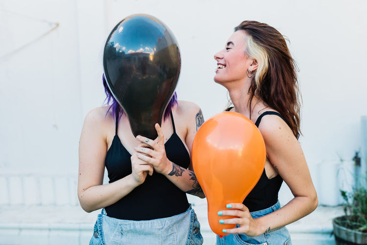 Lesbian women holding balloon while standing outdoors