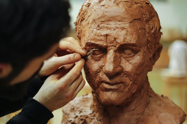 Close up of sculptor finishing a clay head eye in an art studio