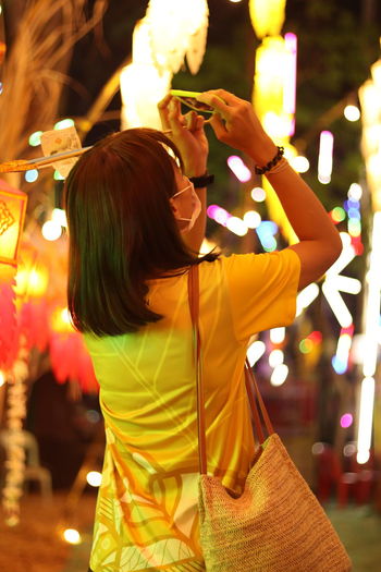 Rear view of woman photographing through smart phone