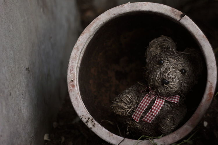 Close-up of abandoned teddy bear clay container
