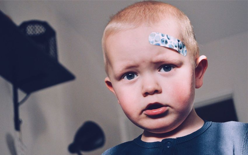 Close-up portrait of boy with bandage on forehead