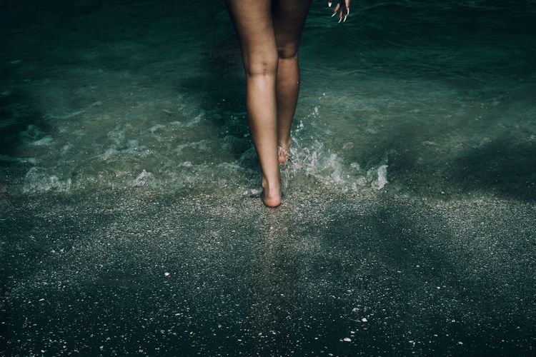 Low section of woman wading in sea