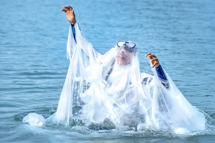 Mature man covered with plastic screaming while swimming in sea
