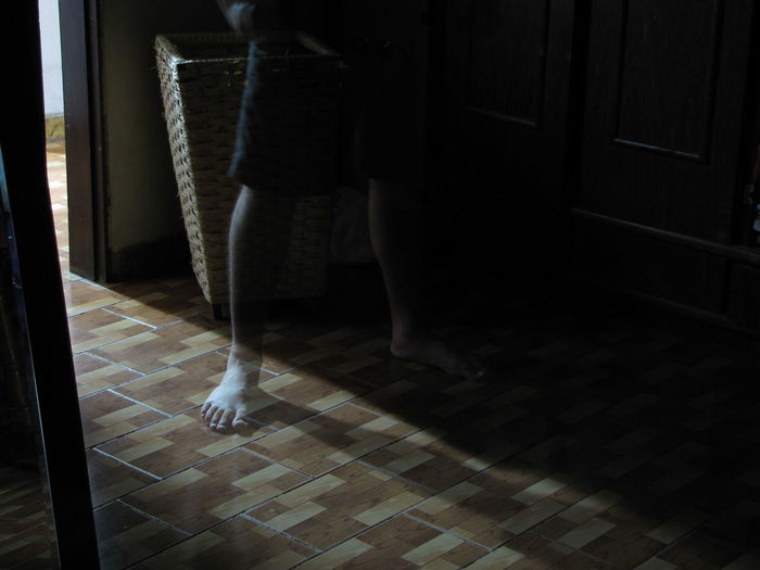 Low section of boy standing on tiled floor at home