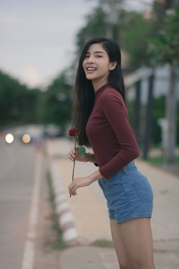 Portrait of smiling woman standing on sidewalk