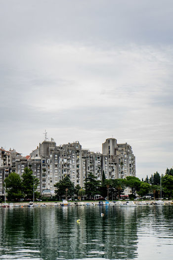 Buildings by lake against sky in city