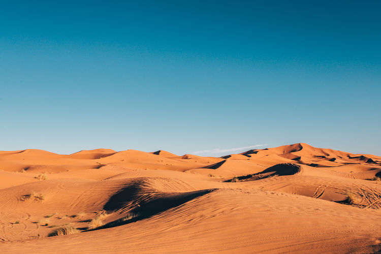 Scenic view of desert against clear blue sky
