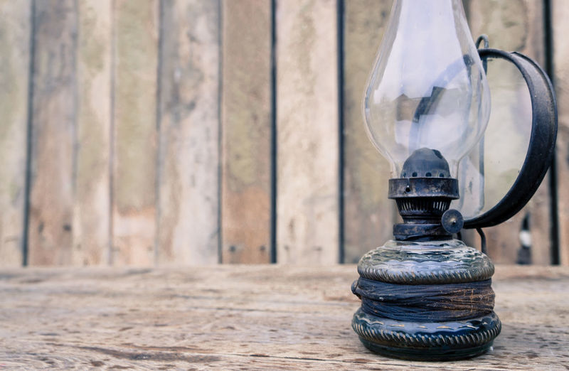 Close-up of old oil lamp on table against wood background