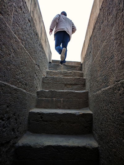 Rear view of man walking on staircase