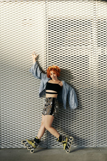 Young alternative redhead with roller skates posing in a metal wall