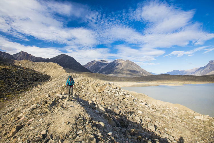 Backpacker hiking across rocky glacial moraine in akshayak pass.
