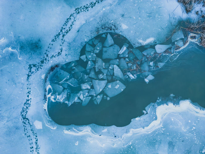 Panoramic aerial view of a frozen lake with animal tracks and cracked ice. 