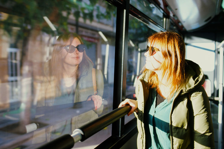 Woman wearing warm clothing while looking through window in bus