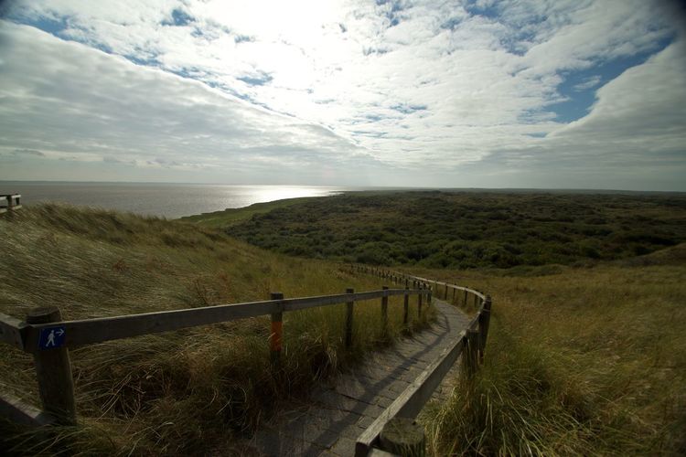Scenic view of land by sea against sky
