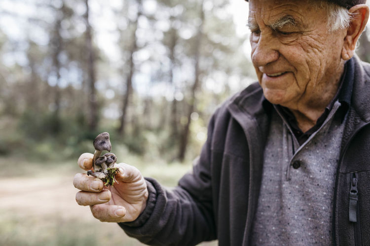 Smiling senior man holding found mushrooms