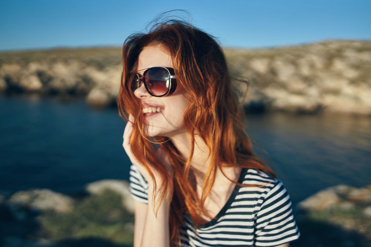 Portrait of young woman wearing sunglasses at sea shore