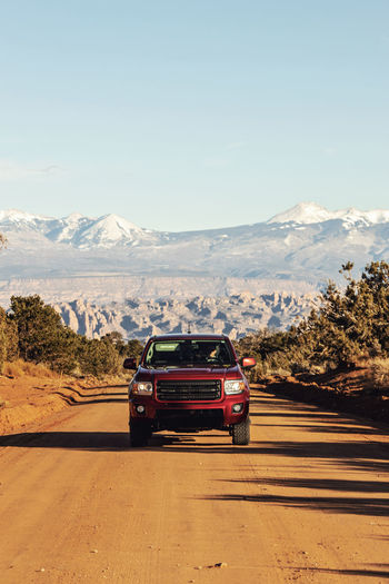 Red pickup truck centered in dirt road in desert near moab utah