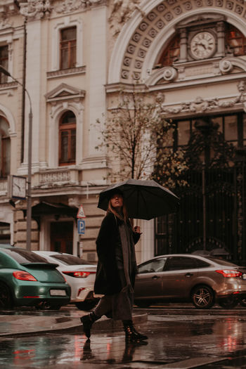 Rear view of woman with umbrella in city