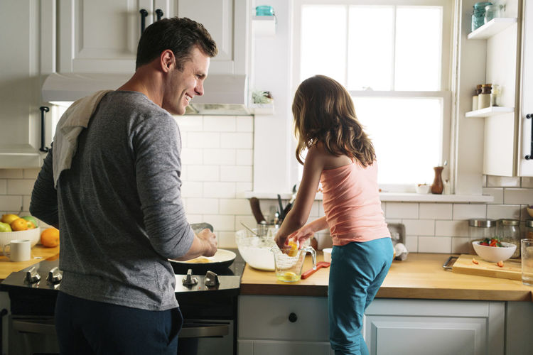 Happy father and daughter preparing food in kitchen at home