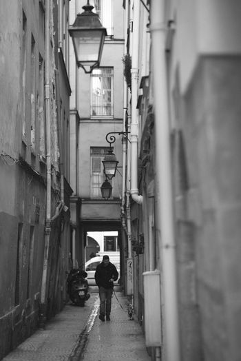 Man walking in alley amidst buildings
