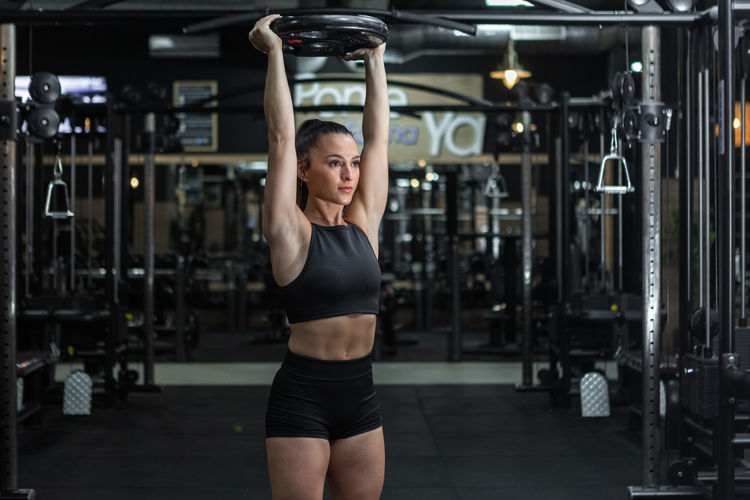 Young woman lifting dumbbell in gym