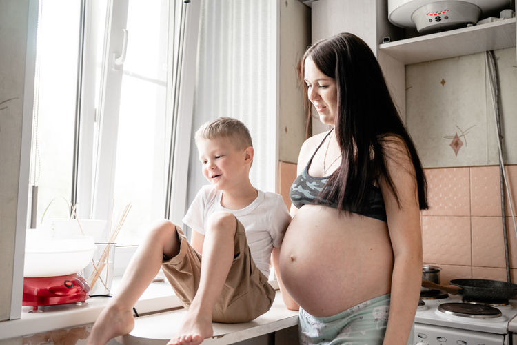 Pregnant mother preparing food with son at home