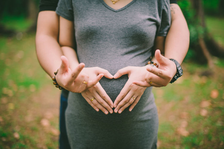 Midsection of couple making heart shape at park