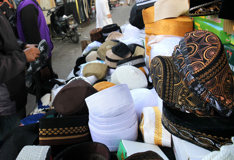 Midsection of men selling skull caps at market stall
