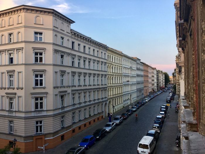 Vehicles on road amidst buildings against sky in city
