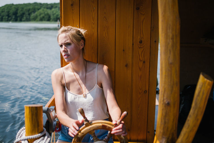 Woman sitting by wheel in boat on lake