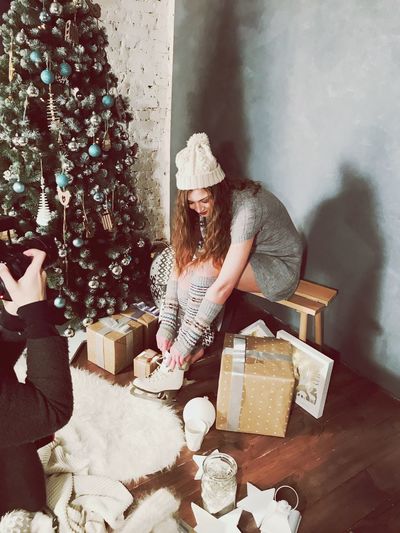 Full length of young woman wearing ice skate by christmas tree