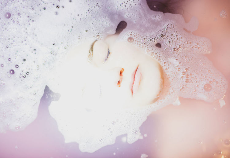 High angle view of woman with eyes closed relaxing in bathtub