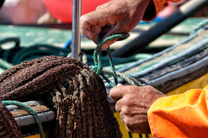 Cropped hands tying rope on boat