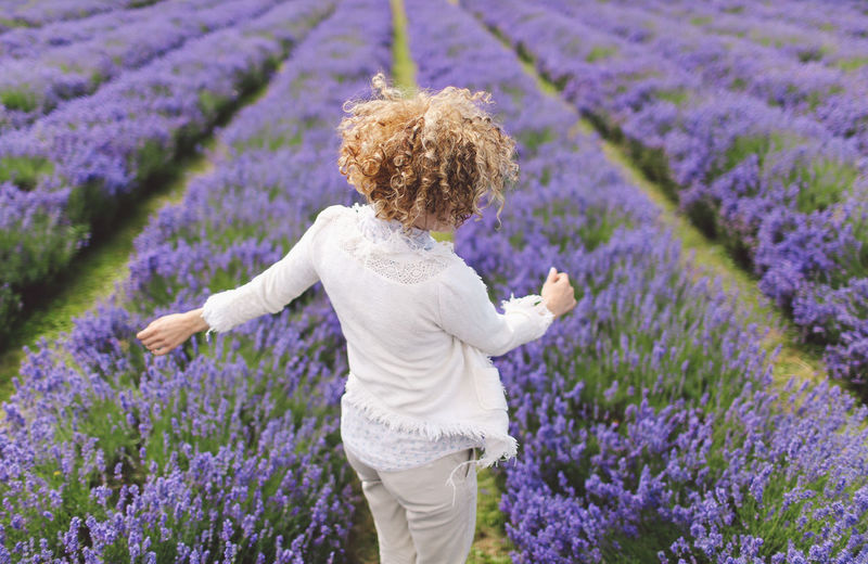 Rear view of woman jumping on lavender field