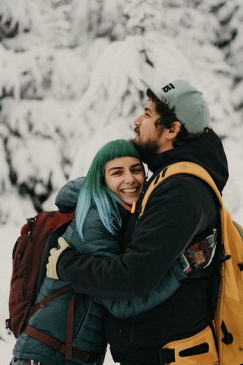 Young couple smiling on snow covered mountains during winter