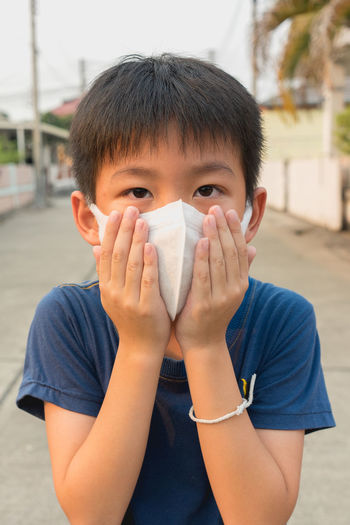 Portrait of boy wearing pollution mask while standing on road
