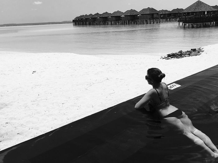 Rear view of woman sitting on beach