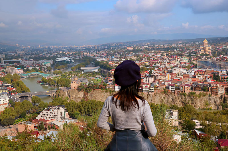 Woman enjoy stunning aerial view with many of iconic landmarks of tbilisi city, georgia