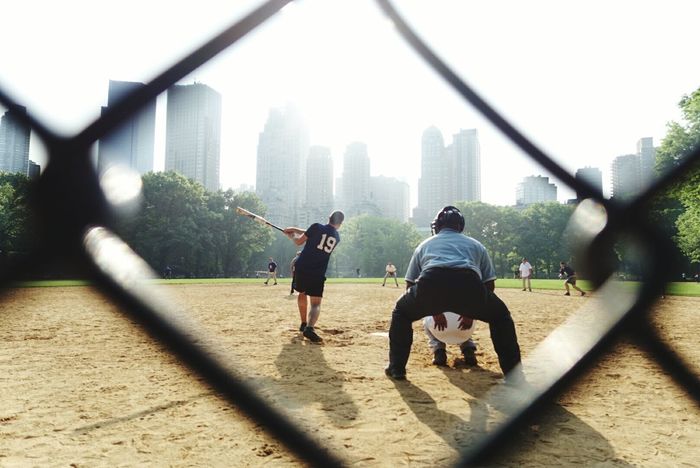 People viewed through fence playing baseball game