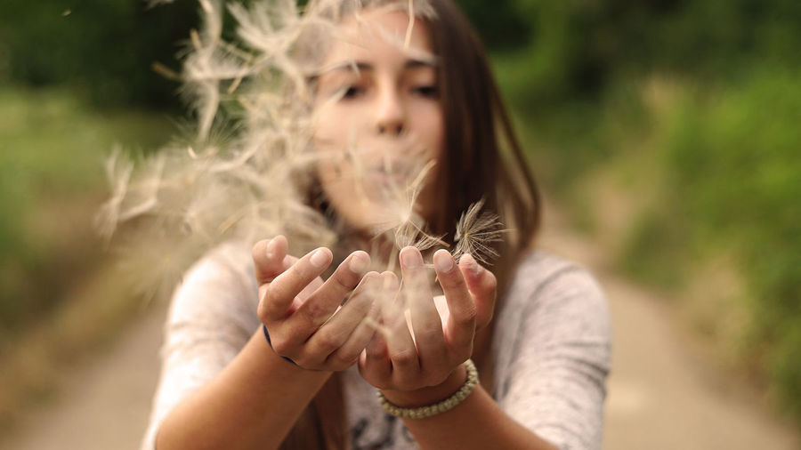 Close-up of woman blowing dandelion seeds