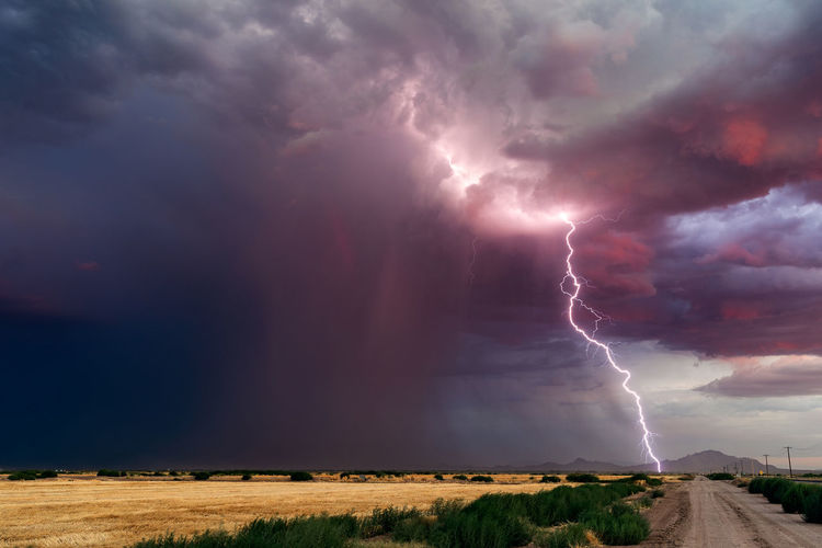 Panoramic view of lightning over landscape against storm clouds
