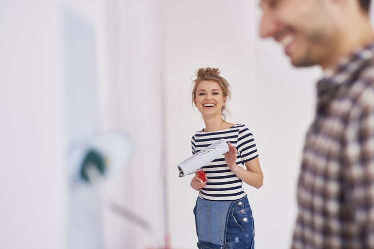 Smiling couple painting wall at home