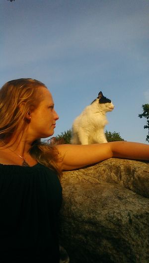 Side view of woman with dog against sky