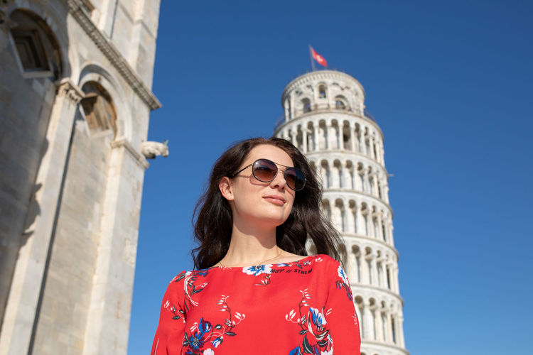 Woman wearing sunglasses while standing against leaning tower of pisa