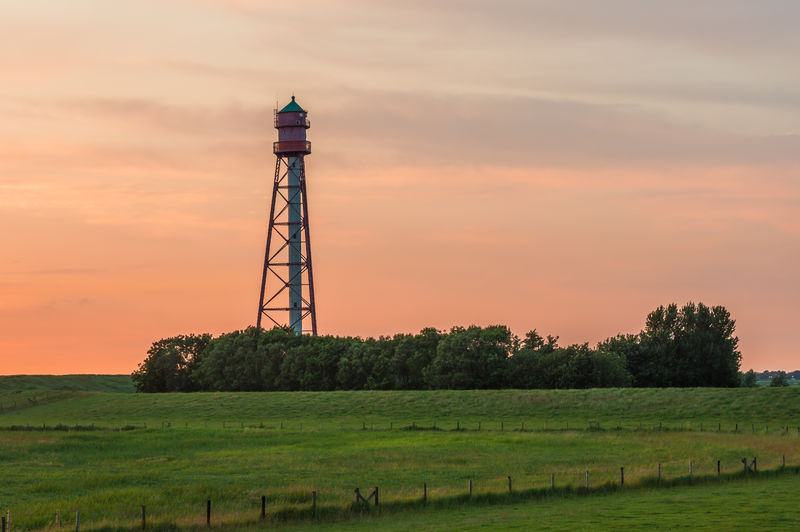 Lighthouse against red sky at dusk, campen, east frisia, lower saxony, germany