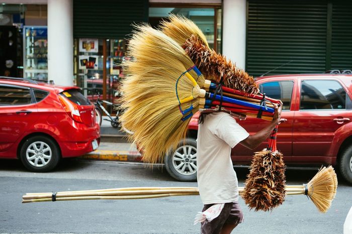 Side view of man with brooms walking on street