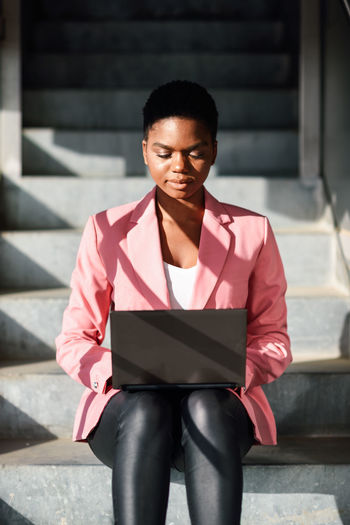 Businesswoman using laptop while sitting on staircase